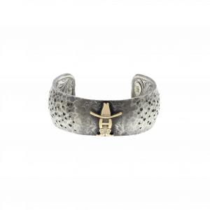 A Clint Orms silver cuff with rounded edges, with H wearing cowboy and and cowboy boots engraved in the silver.