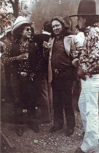 T.C. Cannon, Fritz Scholder, and Earl Biss stand and converse in 1975.